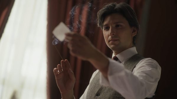 Un illusionista tiene una carta mentre un filo di fumo sale accanto alle sue mani