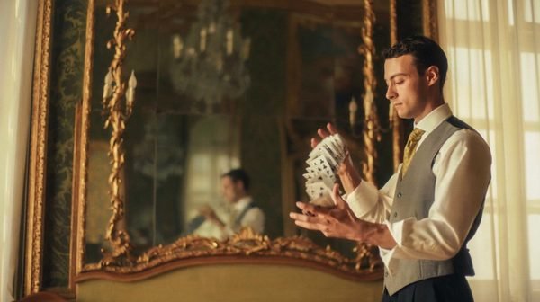 Un illusionista apre un ventaglio di carte davanti a uno specchio dorato